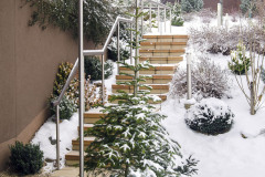 Dom je decentne zapustený do svahu. Vďaka rozmanitým ihličnanom a skalničkám, ktoré zazeleňujú plochú strechu, splýva s okolím tak, že si ho z ulice na prvý pohľad vôbec nevšimnete