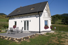 Dom má klasický tvar so sedlovou strechou a symetrické hlavné priečelie s balkónom (typ Ekonomik N7, dispozícia: 4+kk, úžitková plocha: 98 m2, mesačná splátka: 324 Eur)