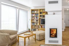 Uprostred hlavnej obytnej miestnosti je obstavaná kozubová vložka Romotop KV 75 s dohrevom teplej vody. Centrálne umiestnenie kozubu má pozitívny vplyv na rovnomerné šírenie tepla v dome