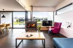 Obývacia izba sa vďaka posuvnému preskleniu otvára do záhrady. Hranicu pozemku uzatvára objekt so saunou a letnou kuchyňou