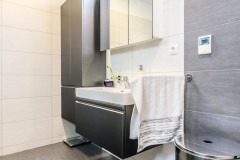 Dizajn kúpeľne sa nesie v kombinácii bridlicovo šedých a svetlých veľkoformátových dlaždíc, tomu zodpovedá aj zvolený odtieň kúpeľňového nábytku