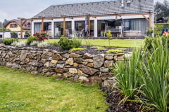 S klesaním pozemku sa stavebníci vyrovnali pomocou kamenného múru murovaného nasucho. Vznikol tak rovinatý rekreačný trávnik lemovaný pôvabnou skalkou