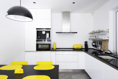 Čistá biela plocha kuchynskej linky zväčšuje malý priestor, jasné žlté akcenty oživujú neutrálnu sivobielu farebnosť celého interiéru