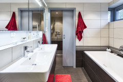 Na poschodí sú dve kúpeľne, s vaňou a so sprchovým kútom. Aj sem prenikla kombinácia sivej, bielej a čiernej farby s prírodným drevom.